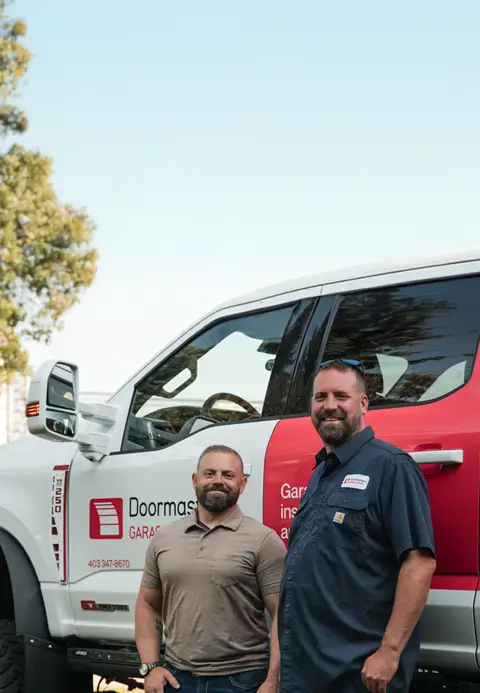 Doormasters Garage Doors Red Deer owners standing in front of their service truck
