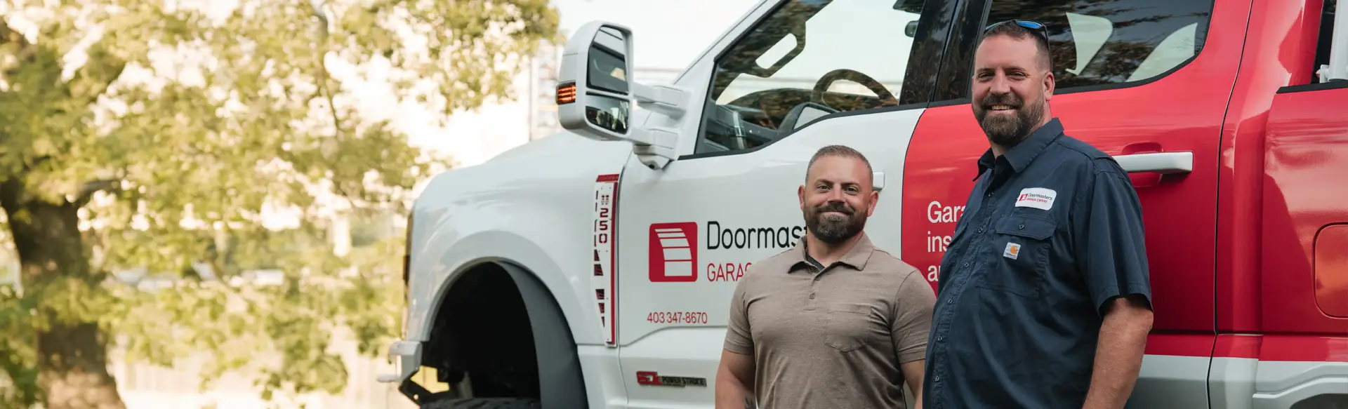Doormasters Garage Doors Red Deer owners standing in front of their service truck